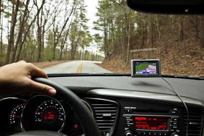 Garmin GPS mounted to the front windshield of a car driving through the woods